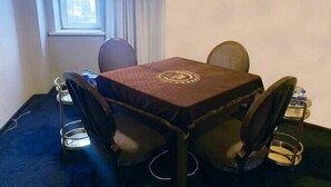 Un petit coin repas avec une table et quatre chaises, une fenêtre avec des rideaux et un distributeur d’eau posé sur la table.