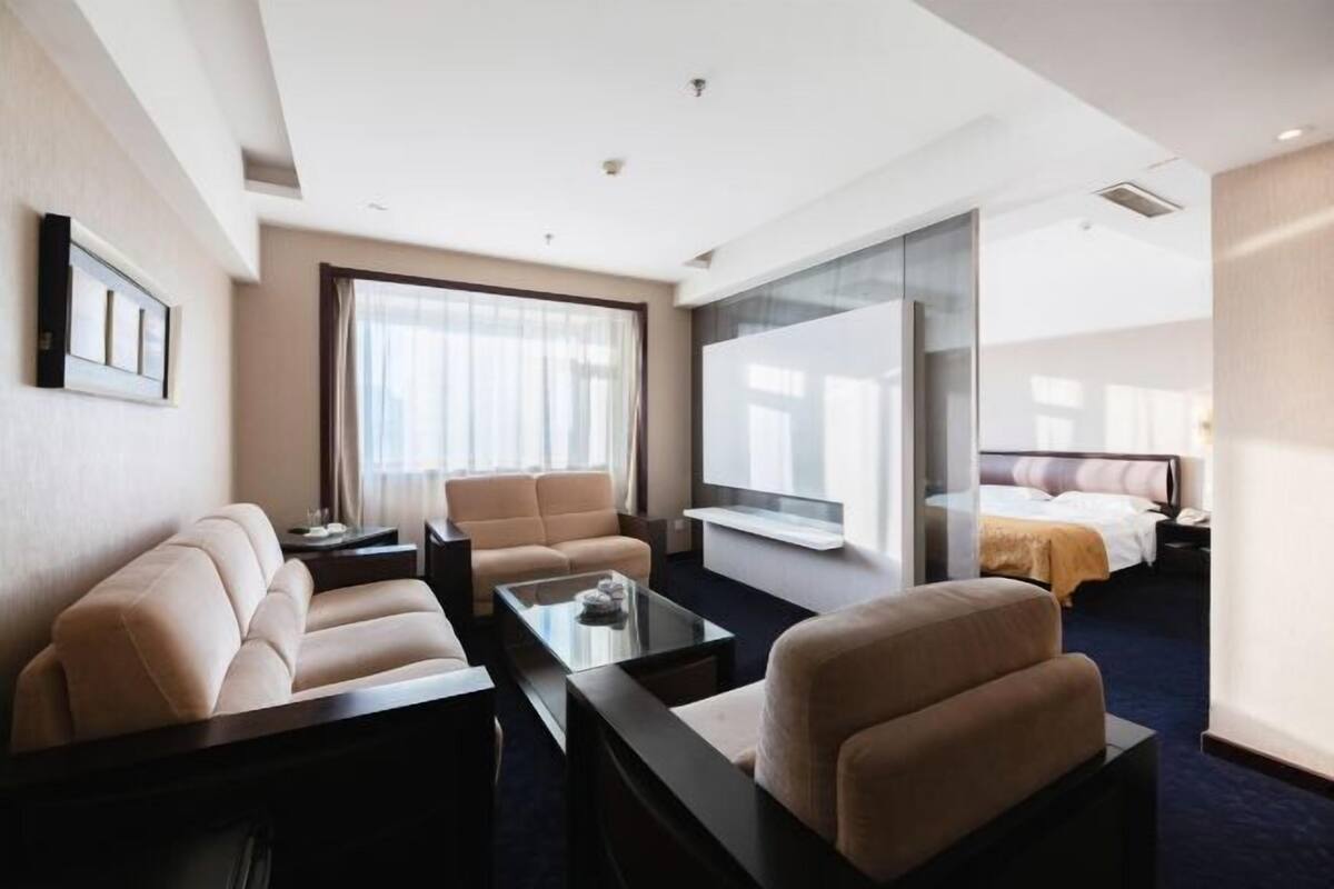 A hotel room with a sofa, armchair, and a bed.