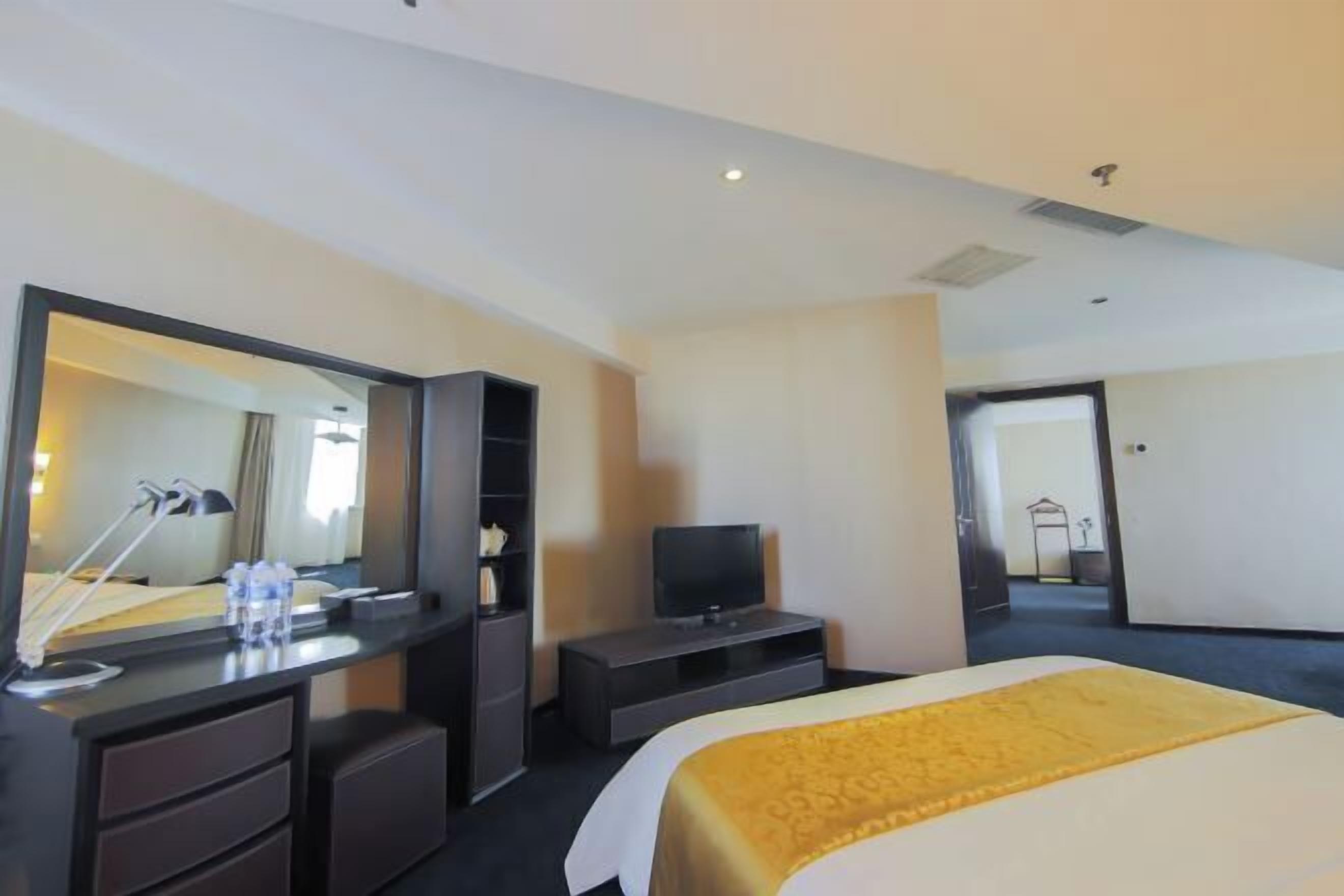 Une chambre d’hôtel comprenant un lit, une télévision, un bureau avec un miroir et une armoire.