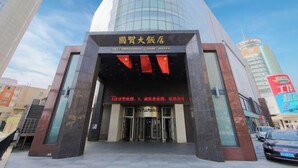 L’entrée de l’hôtel International, avec sa façade moderne en verre et une enseigne chinoise traditionnelle au-dessus des portes.