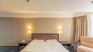Une chambre d’hôtel avec un grand lit, deux tables de chevet, une petite table et un canapé.