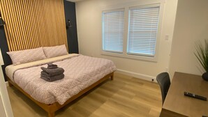 A bedroom with a bed, a ceiling fan, a window with blinds, and a small table with a remote control. - 10 Burnett Home (Rome)