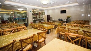 A dining area with multiple tables and chairs, a television mounted on the wall, and a kitchen area in the background. - Yihao Hotel (Shanghai Huinan subway station store) (Shanghai)