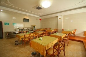 A dining area with multiple tables and chairs, a buffet counter, and a projection screen on the wall. - Yihao Hotel (Shanghai Huinan subway station store) (Shanghai)