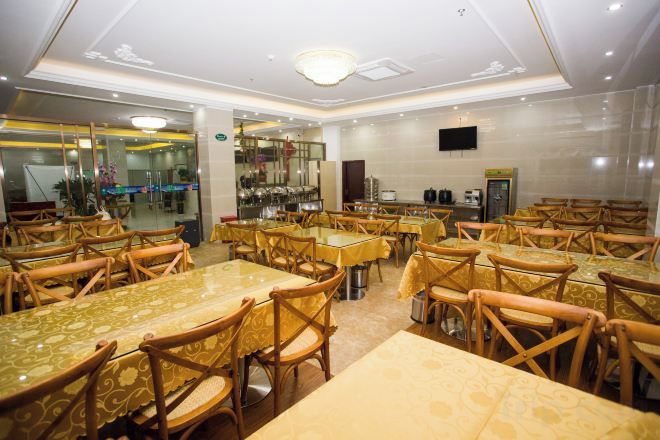 A dining area with multiple tables and chairs, a bar, and a television screen.