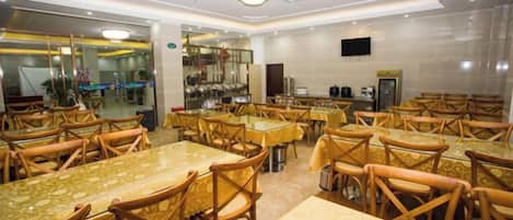A dining area with multiple tables and chairs, a bar, and a television screen.