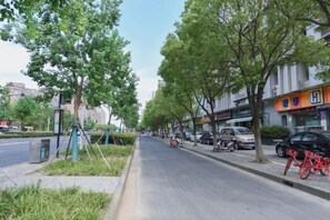 A tree-lined street with parked cars and a bicycle. - Yihao Hotel (Shanghai Huinan subway station store) (Shanghai)