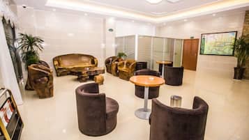 A hotel lobby with a reception desk, seating area with sofas and chairs, and a large map on the wall.