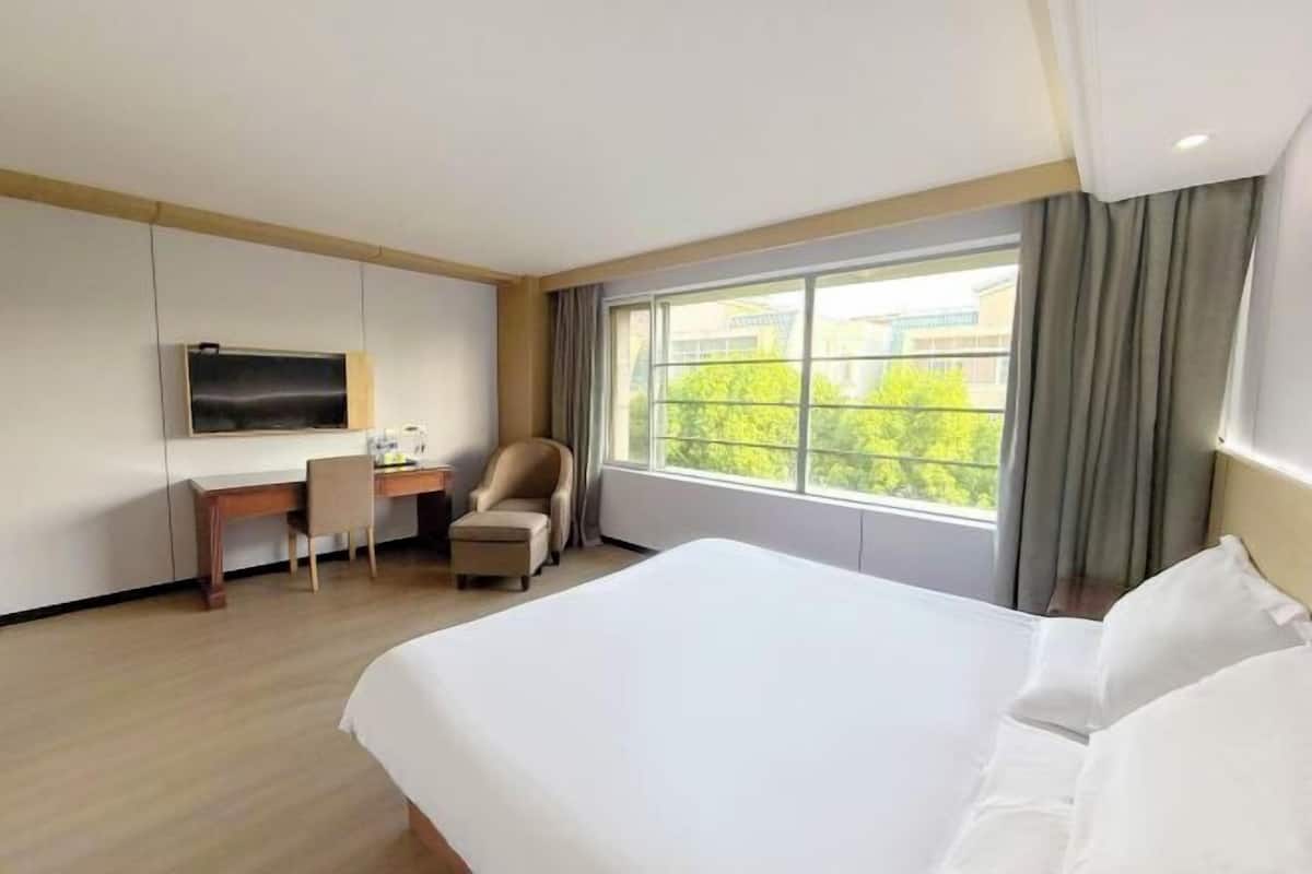 A hotel room with a bed, a desk, a chair, and a TV on the wall.