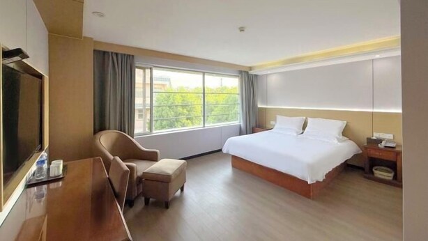 A hotel room with a bed, a desk, a chair, a TV, and a window with curtains. - Yihao Hotel (Shanghai Huinan subway station store) (Shanghai)