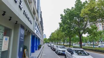 Rua com carros estacionados e um edifício com placas.