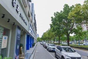 A street with parked cars and a building with signage. - Yihao Hotel (Shanghai Huinan subway station store) (Shanghai)