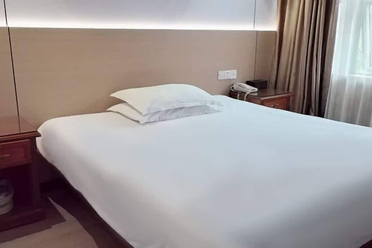 A neatly made bed with white linens in a hotel room.