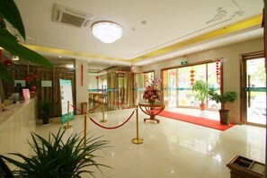 A hotel lobby with a red carpet, potted plants, and a reception desk. - Yihao Hotel (Shanghai Huinan subway station store) (Shanghai)