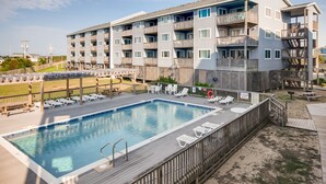 Un hotel de varios pisos con piscina, asientos al aire libre y una terraza.