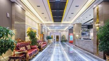 A hotel lobby with a marble floor, plush seating, and a reception desk.