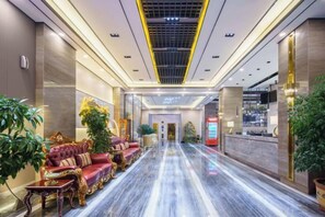 A hotel lobby with a marble floor, plush seating, and a reception desk.