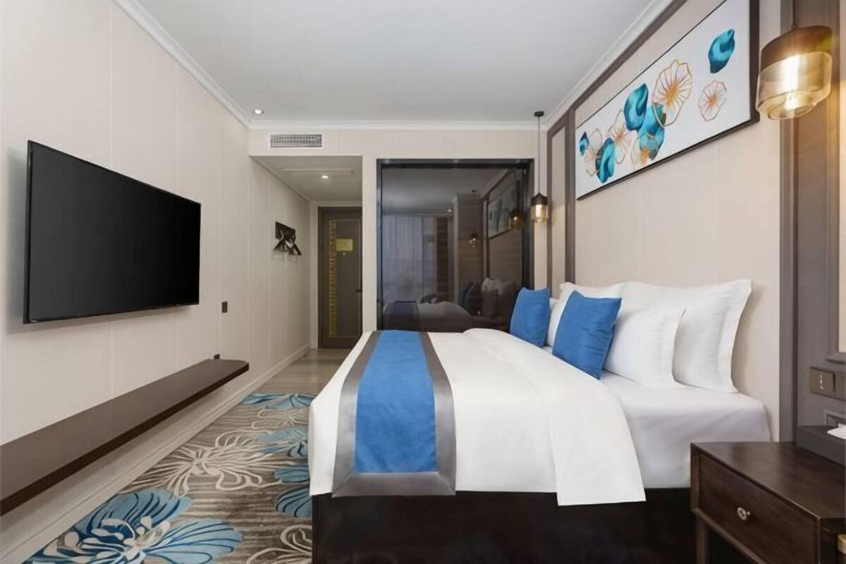 Habitación de hotel con una cama grande, un televisor de pantalla plana, un escritorio y un cuadro en la pared.