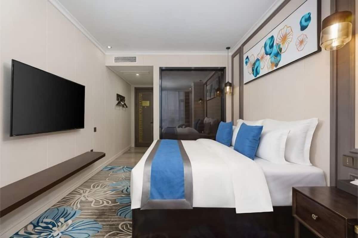 Habitación de hotel con una cama grande, un televisor de pantalla plana, un escritorio y un cuadro en la pared.