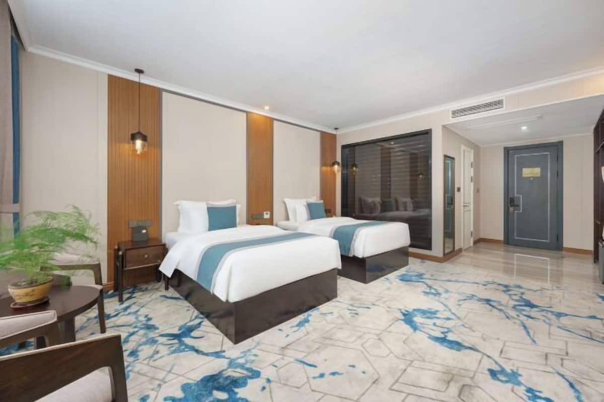 Una habitación de hotel con dos camas, un comedor y un baño.