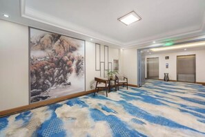 Vestíbulo de hotel con un cuadro grande, una recepción y una alfombra estampada.