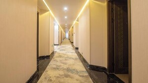 A long, narrow hallway with a patterned carpet and a series of doors on one side.