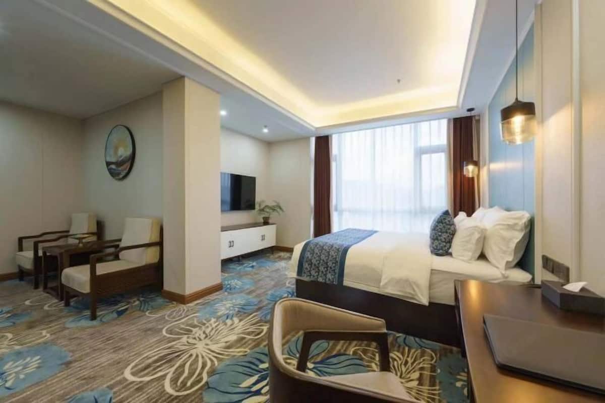 Una habitación de hotel con cama, escritorio, televisión y zona de estar.