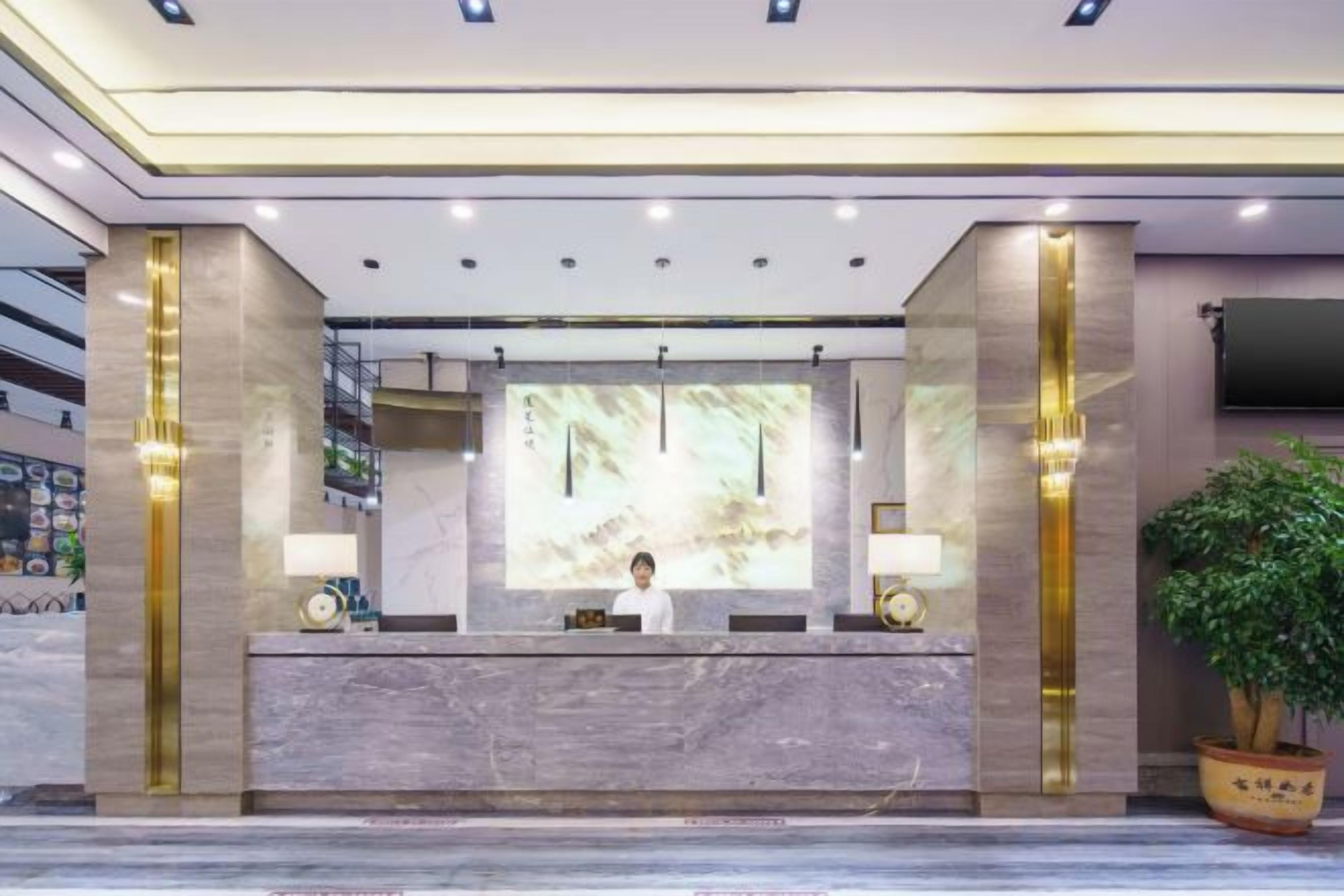 A hotel reception area with a marble counter, a large screen, and a reception desk.