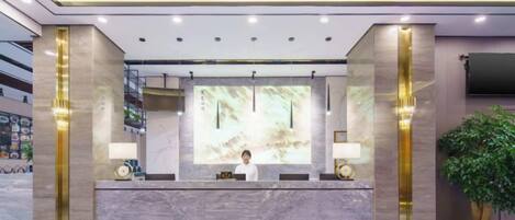 A hotel reception area with a marble counter, a large screen, and a reception desk.