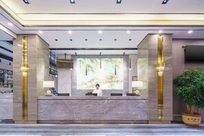 A hotel reception area with a marble counter, a large screen, and a reception desk.