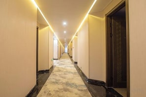 Un pasillo de hotel con piso alfombrado, puertas a ambos lados e iluminación en el techo.