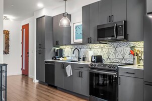 Cozinha moderna com armários cinza, micro-ondas preto e forno Samsung.