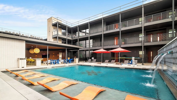 A modern hotel with a rooftop pool, multiple balconies, and outdoor seating areas. - The Mercer (New Braunfels)