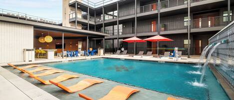 Een buitenzwembad, parasols bij het zwembad en ligstoelen