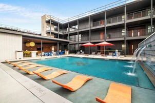 Um hotel moderno com piscina no terraço, várias varandas e áreas de estar ao ar livre.