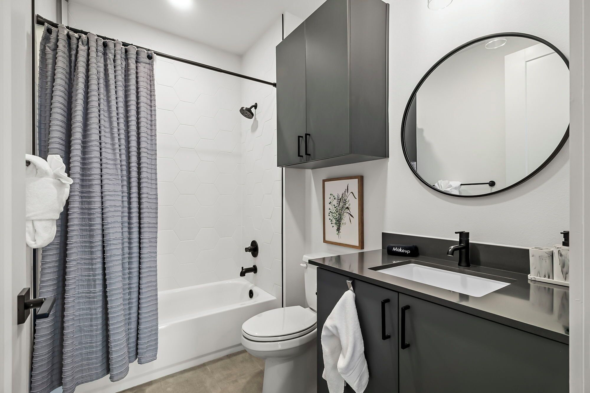 A modern bathroom with a bathtub, toilet, and vanity with a sink.