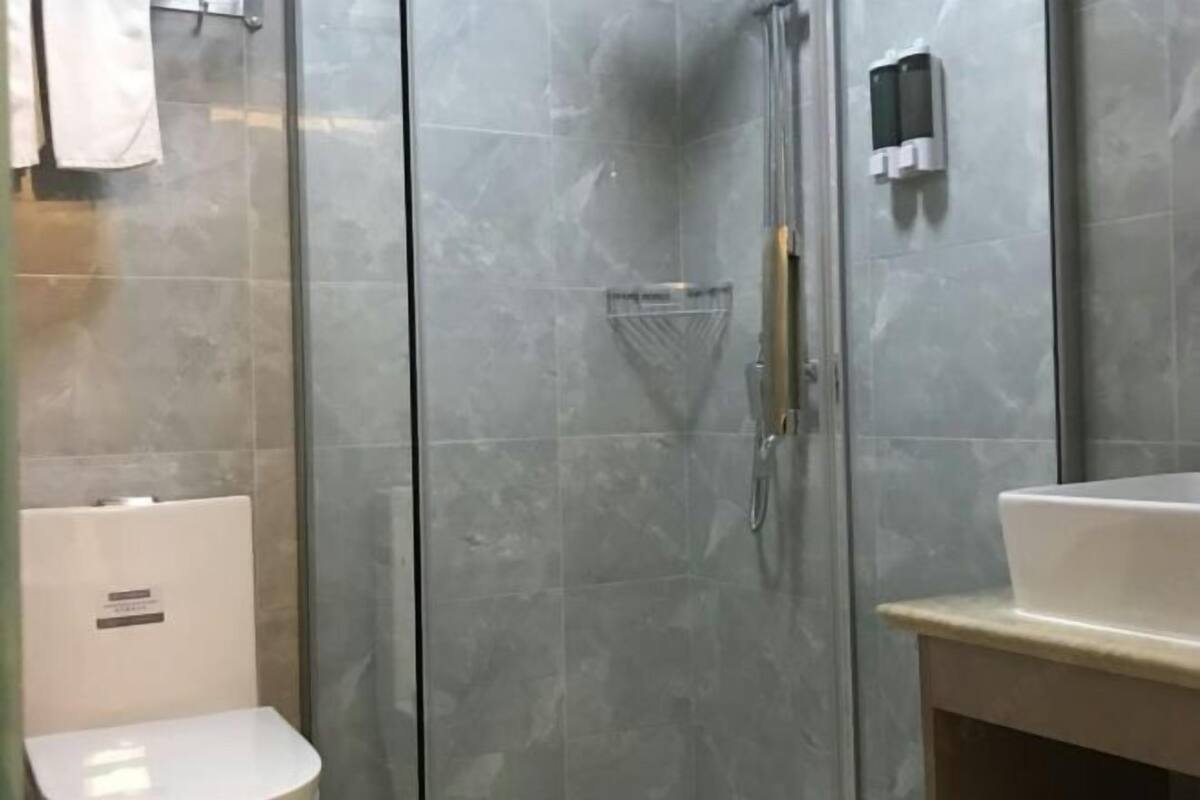 A bathroom with a glass-enclosed shower, a white sink, and a towel rack.