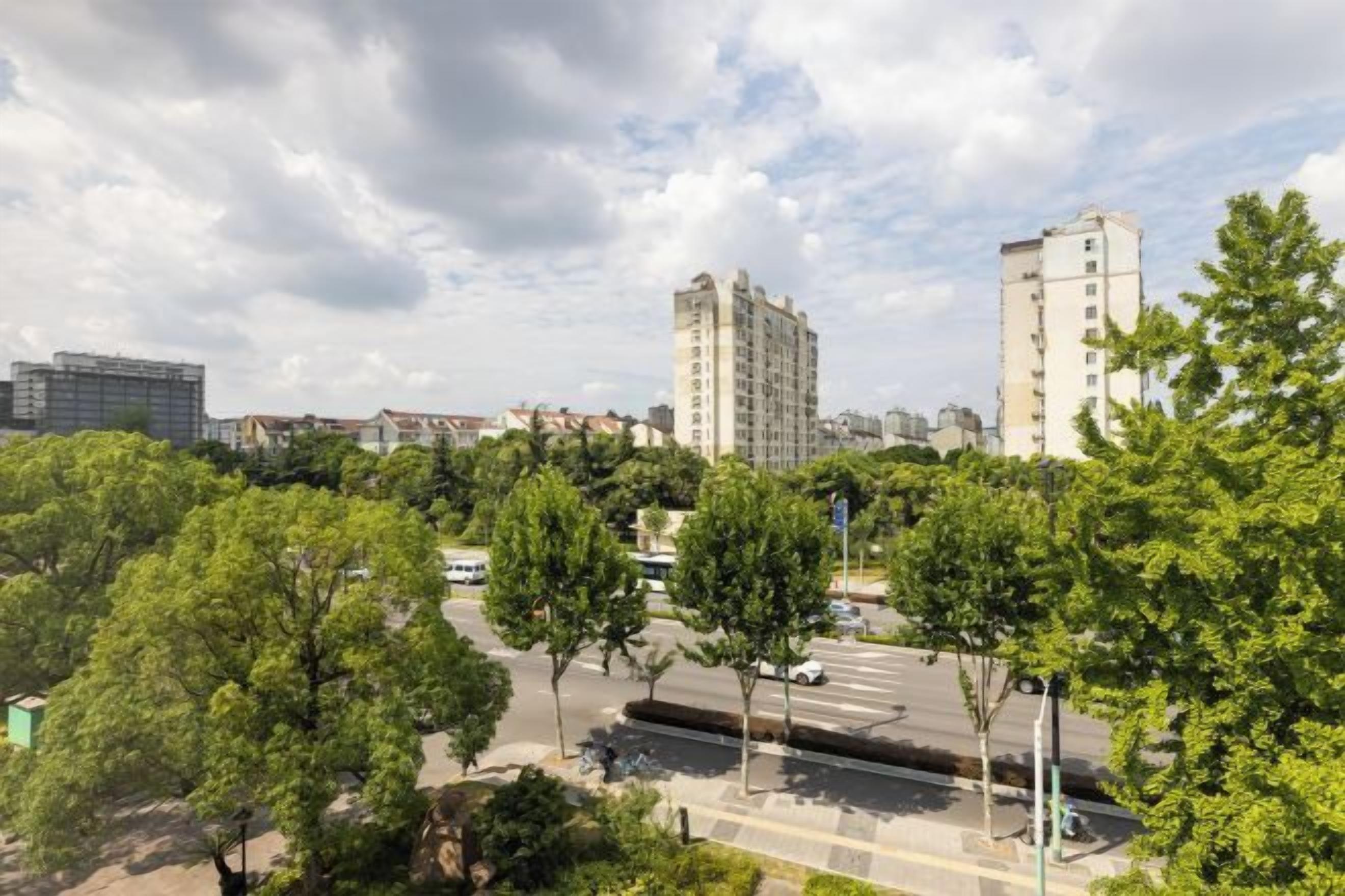 Un paysage urbain avec de hauts immeubles, une route et des arbres verdoyants.