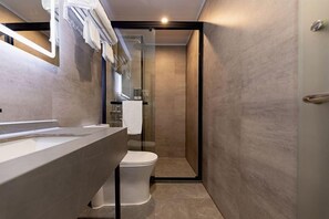 Um banheiro moderno com box de vidro, vaso sanitário branco e um espelho grande sobre a pia.