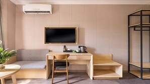 A modern, minimalist room with a wooden desk, a comfortable seating area, and a mounted TV. - Yizhou Hotel (Shanghai)
