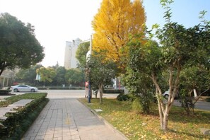 A paved pathway with trees and a building in the background.
