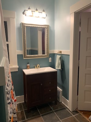 Un baño con tocador, espejo y lámpara sobre el espejo.