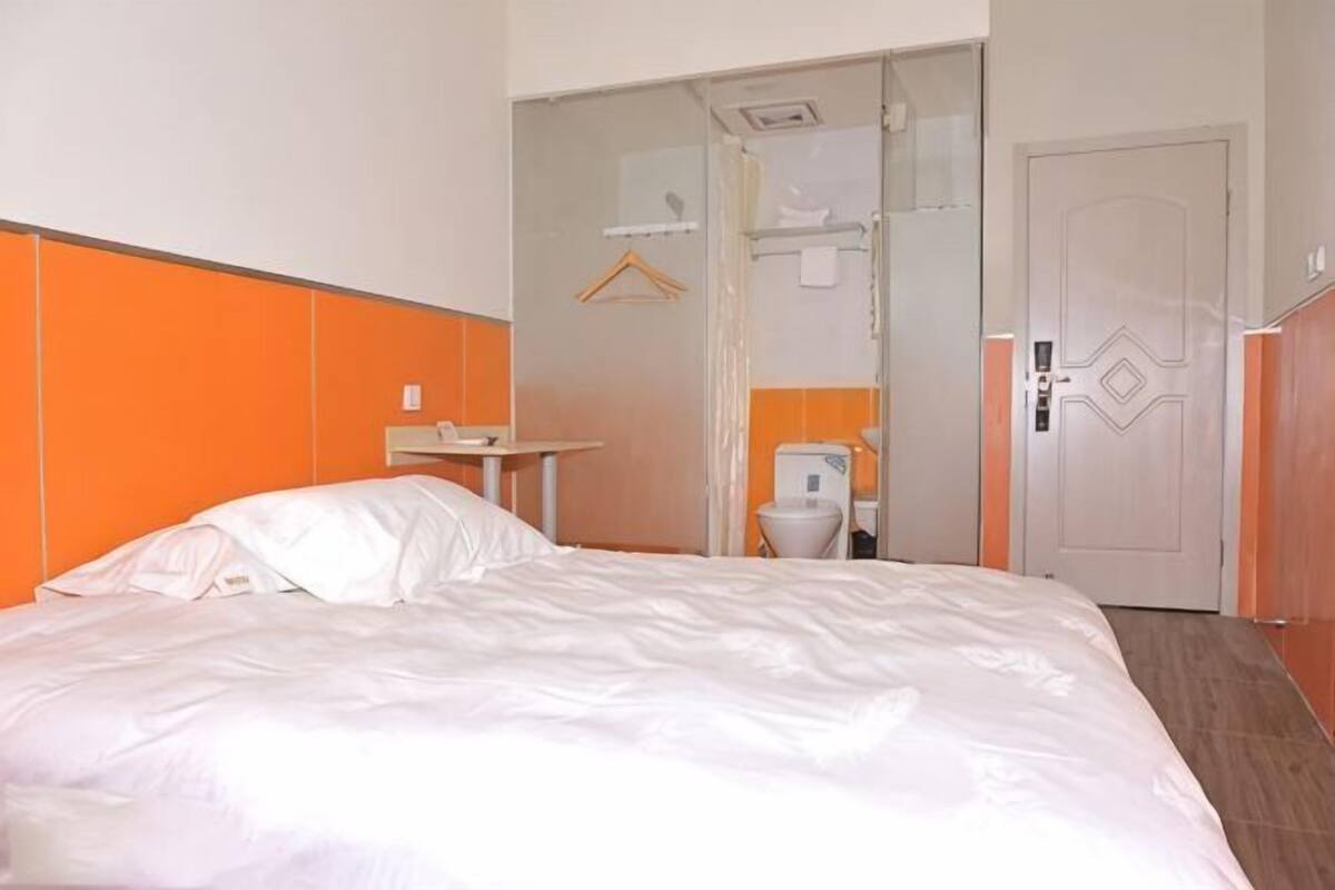 A hotel room with a bed, a small table, a toilet, and a door.