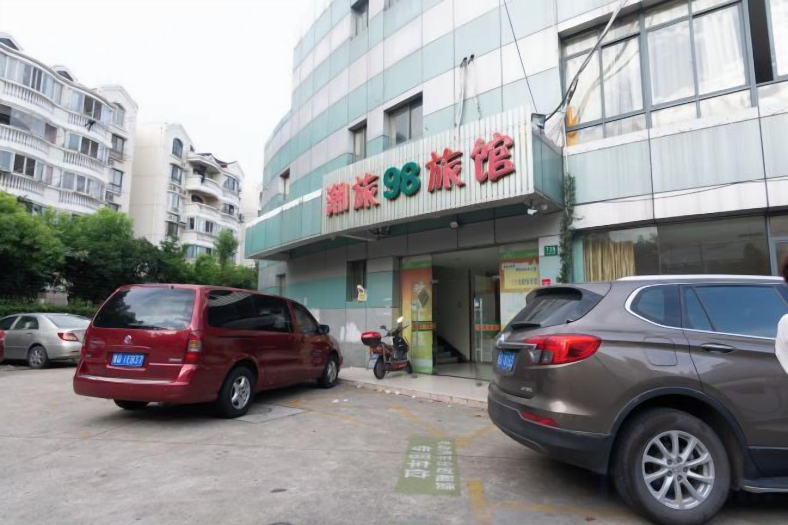A building with a sign that reads 'Tangshan 93 Hotel'. There are cars parked in front.