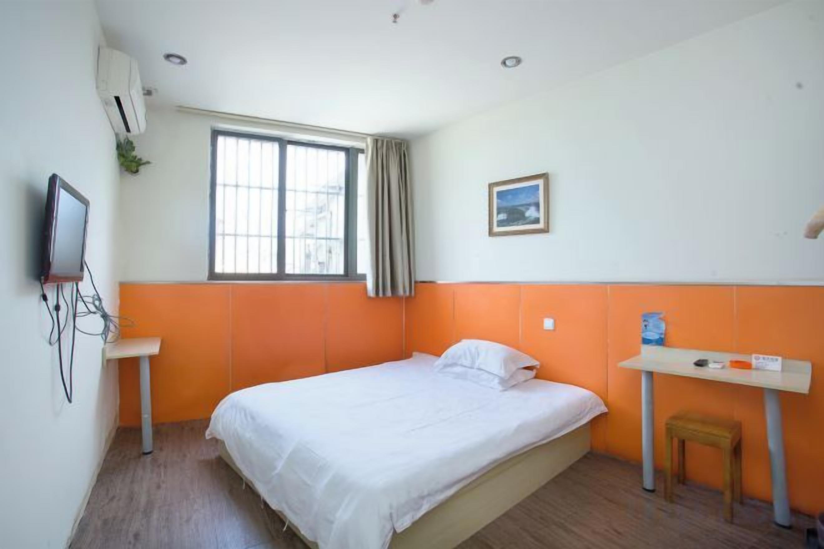 Ein Hotelzimmer mit einem Bett, einem Schreibtisch, einem Sessel, einem Fernseher und einem Fenster mit Vorhängen.
