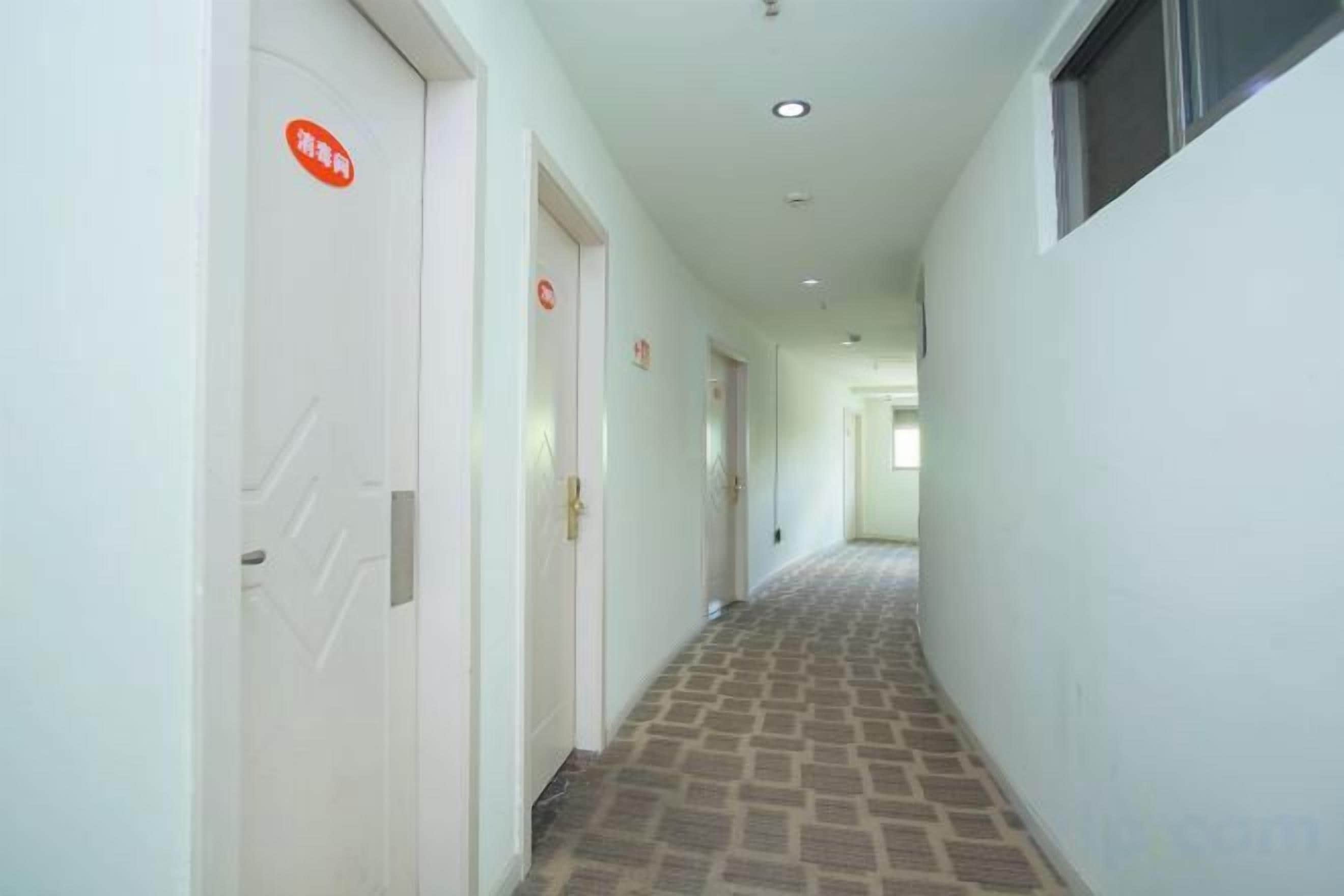 A hallway with doors, a tiled floor, and a ceiling with recessed lighting.