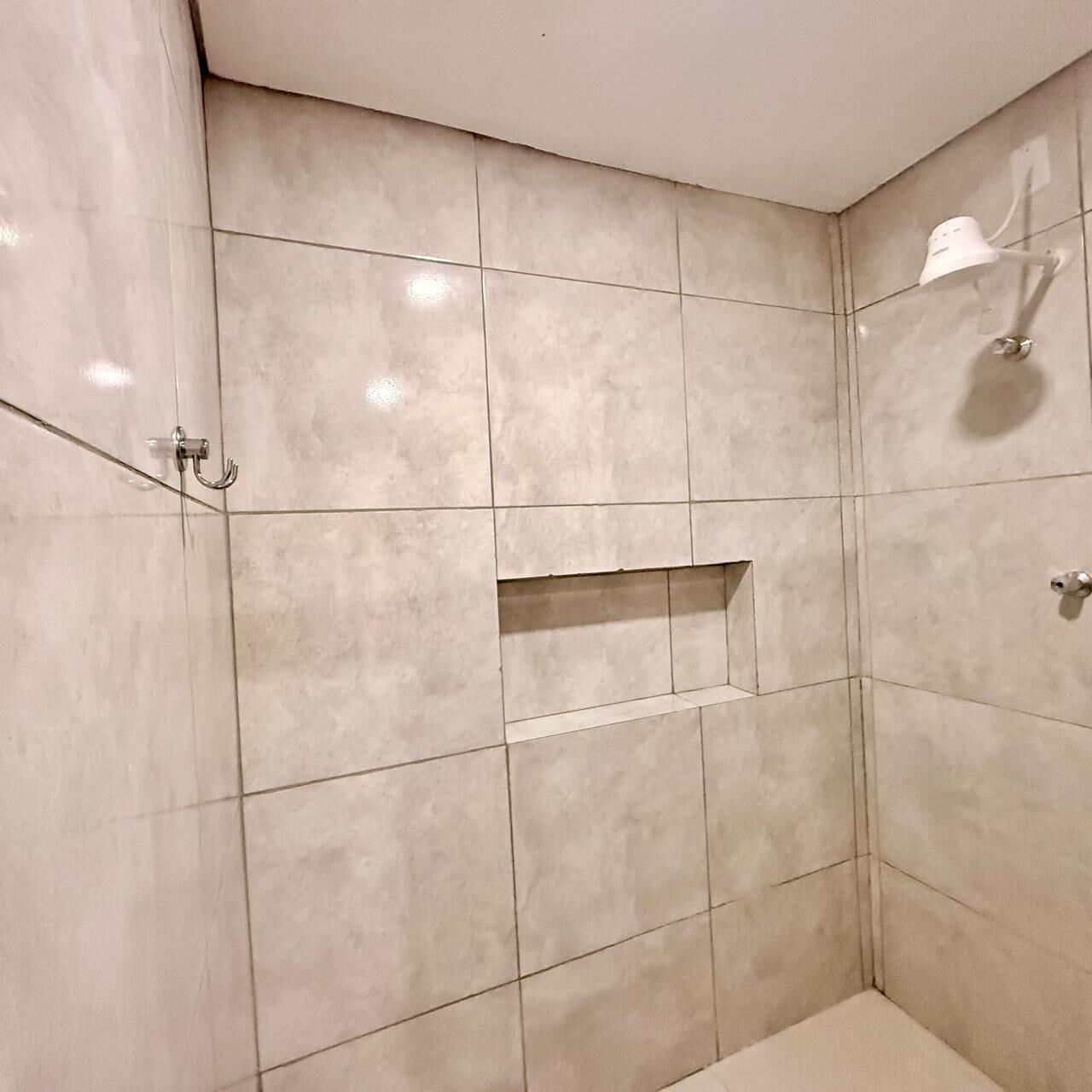 Un baño con paredes de azulejos, zona de ducha y toallero.
