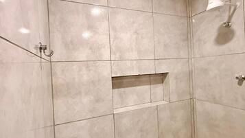 Un baño con paredes de azulejos, zona de ducha y toallero.