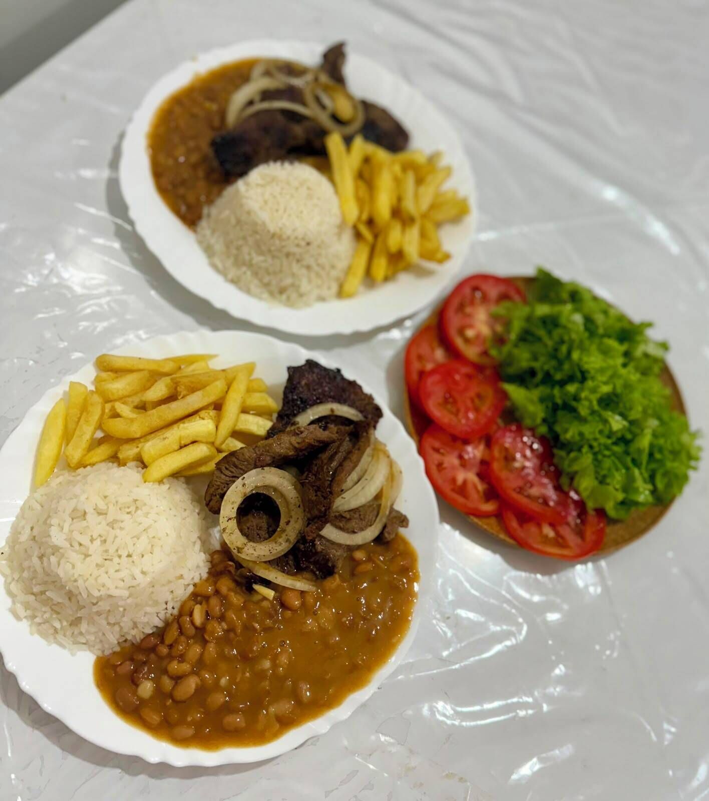 Un plato de arroz, frijoles, papas fritas y carne.