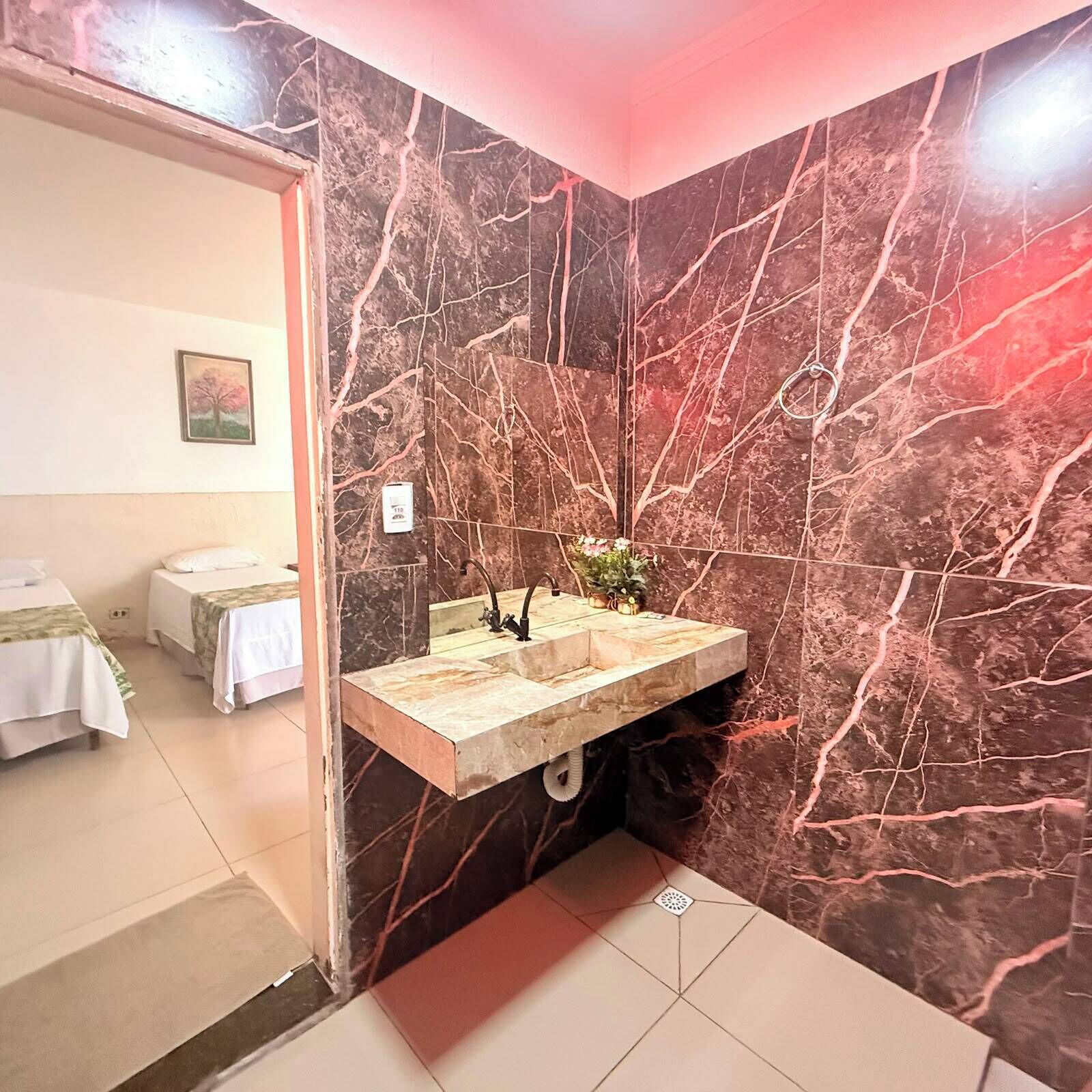 A bathroom with a marble sink, a mirror, and a small plant.